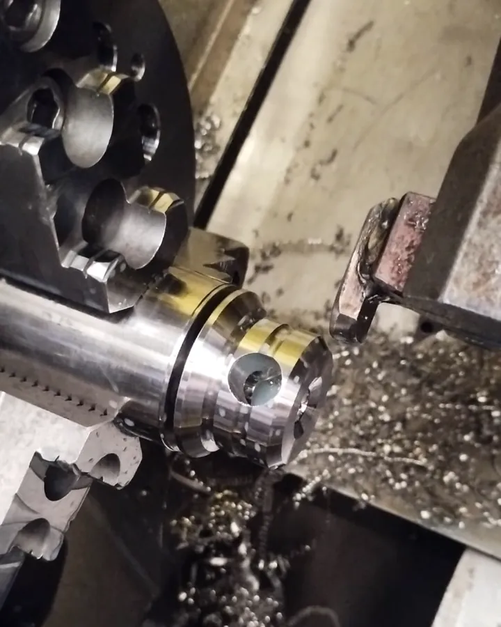 Pieza de acero sujeta en el plato de un torno CNC con viruta del mecanizado